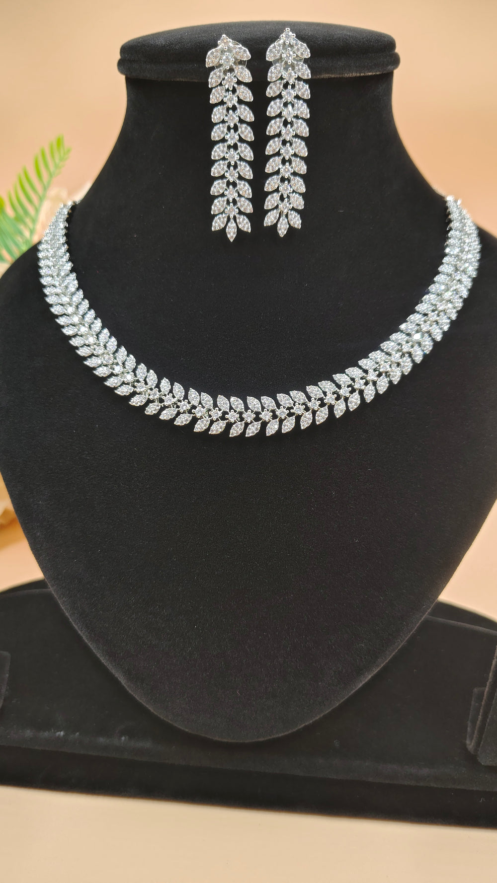 A necklace and earrings displayed elegantly on a black stand, showcasing their intricate design and craftsmanship.