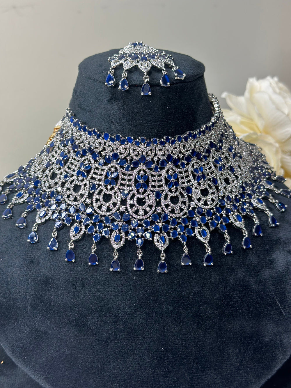 "An elegant silver necklace and matching headpiece, featuring dazzling blue gemstones and intricate detailing, perfect for a sophisticated and striking look."
